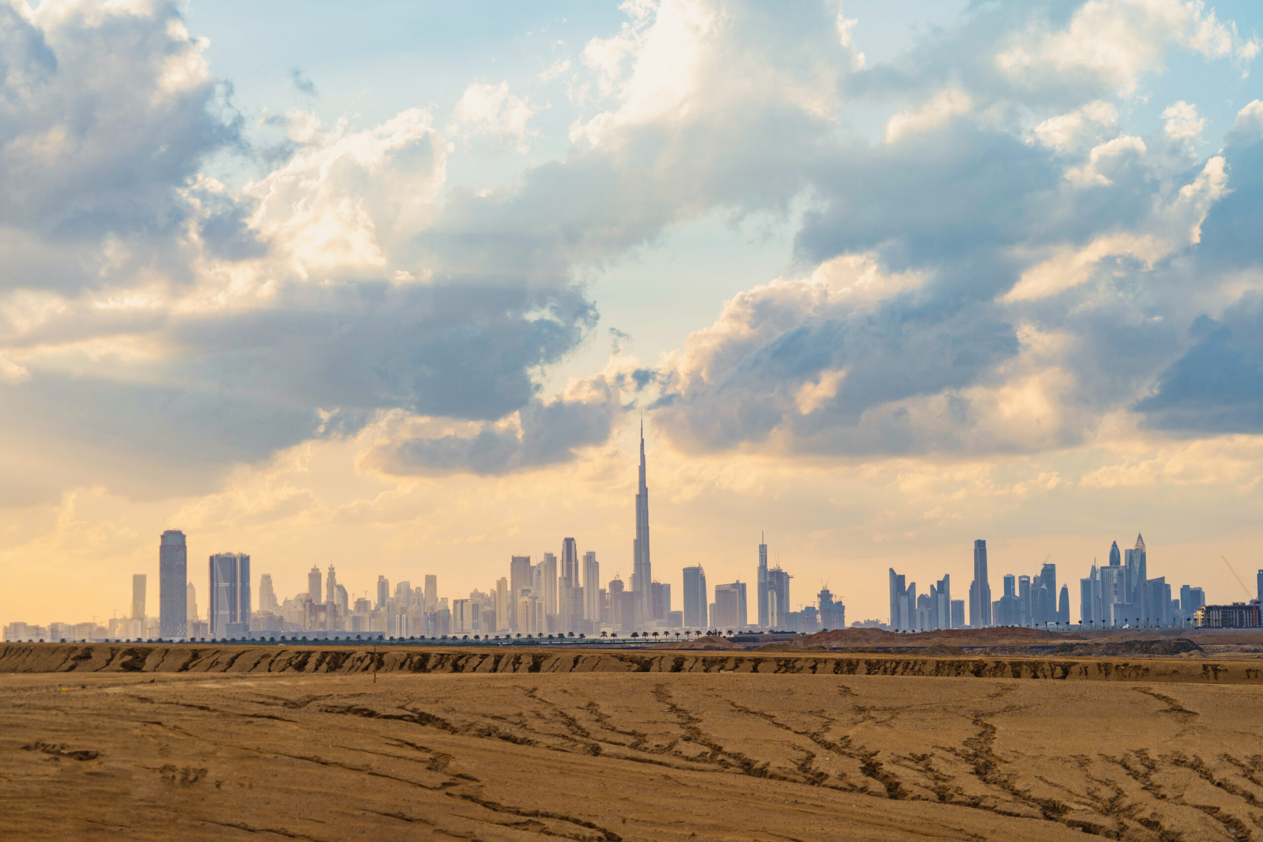 Dubai Downtown skyline with desert sand, United Arab Emirates or UAE. Financial district and business area in smart urban city. Skyscraper and high-rise buildings at sunset.